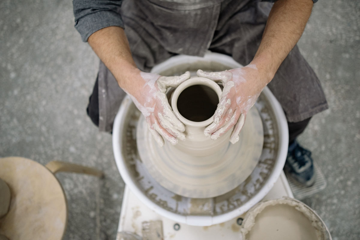 Hands shaping clay on a potter's wheel
